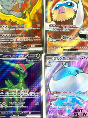 Quatre cartes Pokémon différentes sont disposées en rangée sur une table.