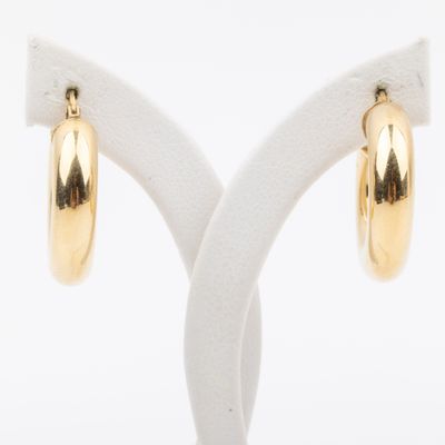 a pair of gold hoop earrings on a white stand