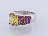 a close up of a yellow sapphire and pink sapphire ring on a white surface
