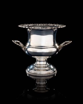 un vase en argent muni d'une anse, posé sur une surface noire