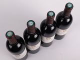 six bottles of wine are lined up in a row on a white surface