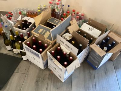de nombreuses caisses de bouteilles et des bouteilles de vin par terre