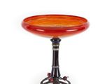 une table orange et noire avec un plateau en verre posé sur un piètement en métal