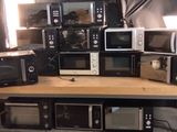 de nombreux micro-ondes et grille-pain empilés sur une table