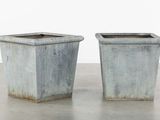 pair of concrete planters on concrete floor with white wall in background