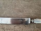 a knife that is sitting on a table next to a silver plate