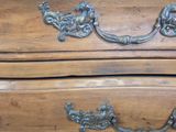 a wooden chest of drawers with ornate handles on it