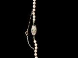 a close up of a necklace with pearls and a locke on a chain