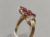 a close up of a gold ring with a ruby and diamond center