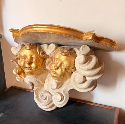 une sculpture dorée et blanche posée sur une étagère près d'un mur