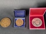 three gold and silver medals in a red box on a black surface