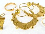 many gold rings and other gold jewelry on a white surface