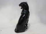 a statue of a black cat sitting on a white surface