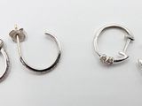 deux paires de boucles d'oreilles créoles en argent posées sur une surface blanche