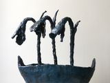 une sculpture représentant trois oiseaux dans un bol posé sur un socle