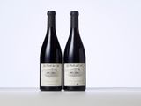 two bottles of red wine sitting on top of a table