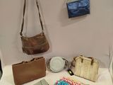 several purses and handbags are arranged on a bed