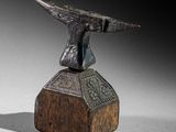 statue en bronze représentant un oiseau posée sur un bloc de bois, sur fond noir