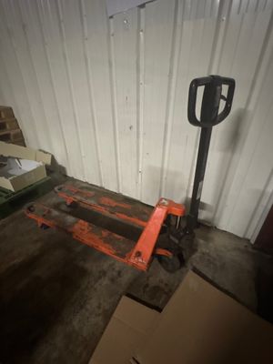un chariot élévateur au milieu d'une pièce où s'entassent des cartons les uns sur les autres