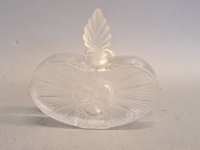 un objet en verre transparent en forme de cœur posé sur une surface blanche