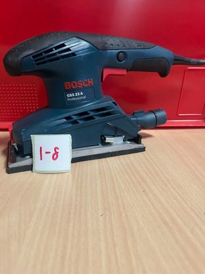 La ponceuse orbitale Bosch est posée sur une table, à côté d'une boîte rouge