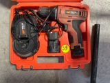 une perceuse sans fil dans une boîte à outils avec un chargeur