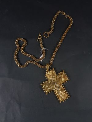 un collier en or orné d'une croix, posé sur une table