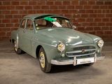 a green car parked in front of a brick wall