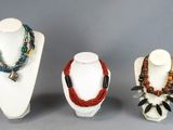 three different necklaces on display on a white mannequin