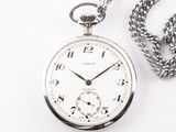 une montre de poche en argent, suspendue à une chaîne, posée sur une surface blanche