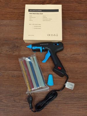 un pistolet à colle sans fil et un paquet de bâtons de colle posés sur une table