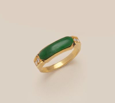 a close up of a gold ring with a green stone