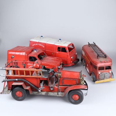 trois camions de pompiers miniatures et un camion de pompiers posés sur une surface blanche