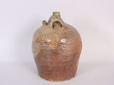 a large brown vase with a handle on a white surface