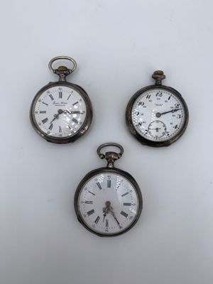 trois montres de poche anciennes posées sur une surface blanche
