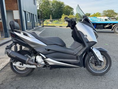 une moto argentée et noire garée devant un immeuble