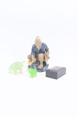 une figurine représentant un vieil homme assis sur une caisse
