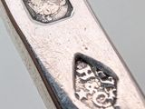 a close up of a silver spoon with a coin on it