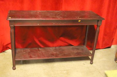 une table en bois surmontée d'une étagère, devant un rideau rouge
