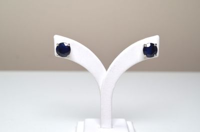 une paire de boucles d'oreilles à clous en saphir bleu, présentées sur un socle blanc