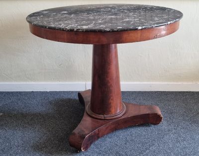 une petite table avec un plateau en marbre posée sur un sol recouvert de moquette