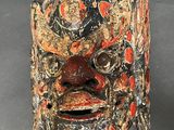 an image of a wooden mask with red and black paint on it