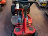 a red lawn mower sitting in a garage with other lawn mowers