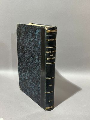 un vieux livre posé sur une table à côté d'un mur blanc