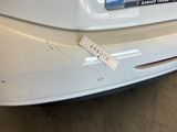 the rear end of a white car with a sticker on it ' s bumper