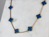 a gold chain necklace with blue flowers on a marble surface