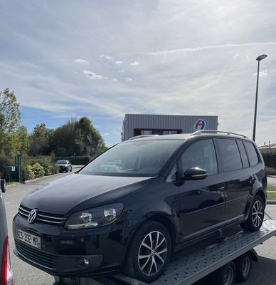 une camionnette noire sur une remorque à plateau dans un parking