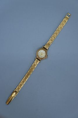 une image représentant une montre-bracelet en or sur un fond bleu