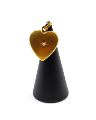 un pendentif doré en forme de cœur suspendu à un cône noir