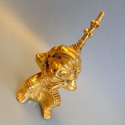 a gold figurine of an elephant holding a stick